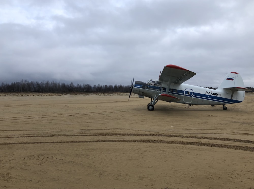 white and red passenger plane on brown field under white clouds during daytime