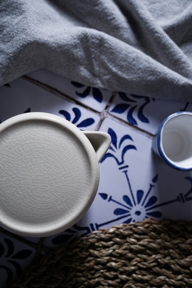 white ceramic mug on white and blue floral table cloth