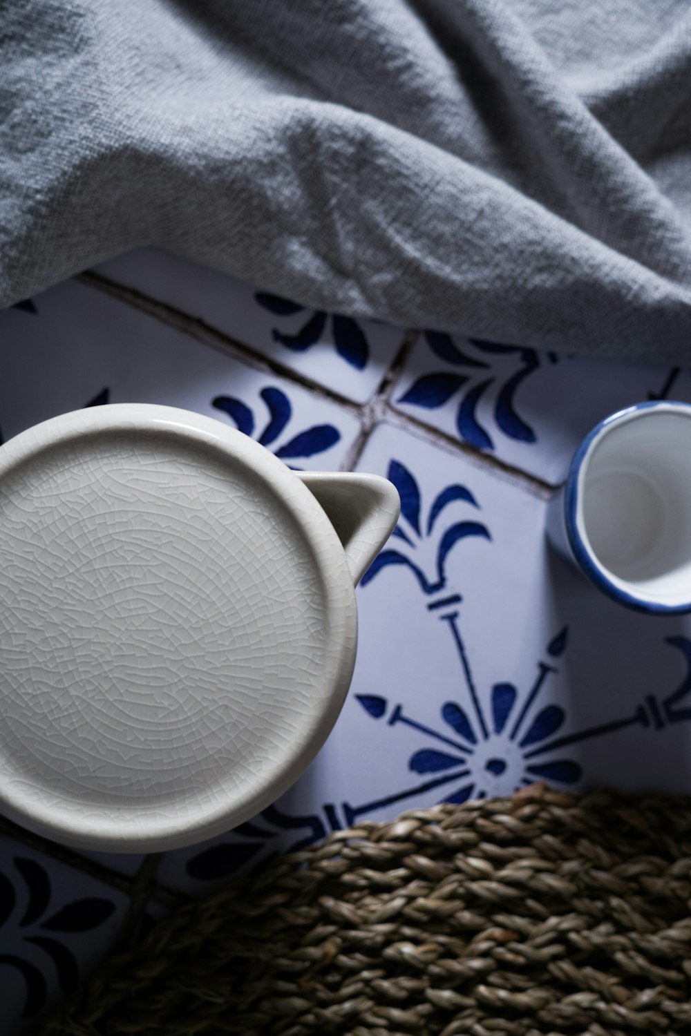 white ceramic mug on white and blue floral table cloth