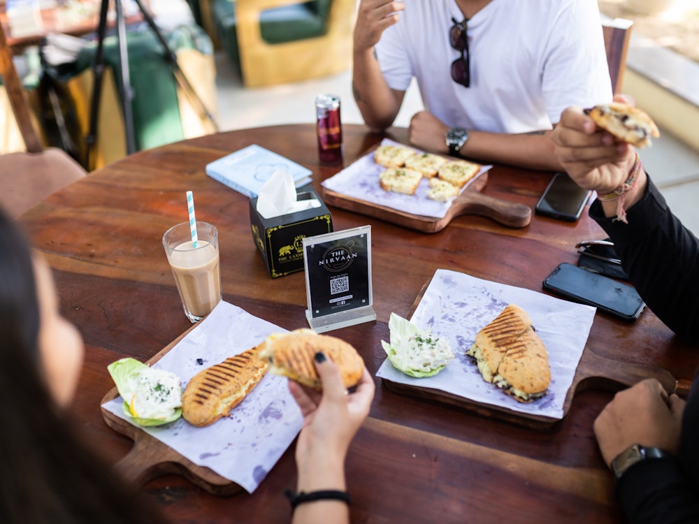 person in white shirt holding bread and fries on brown wooden table