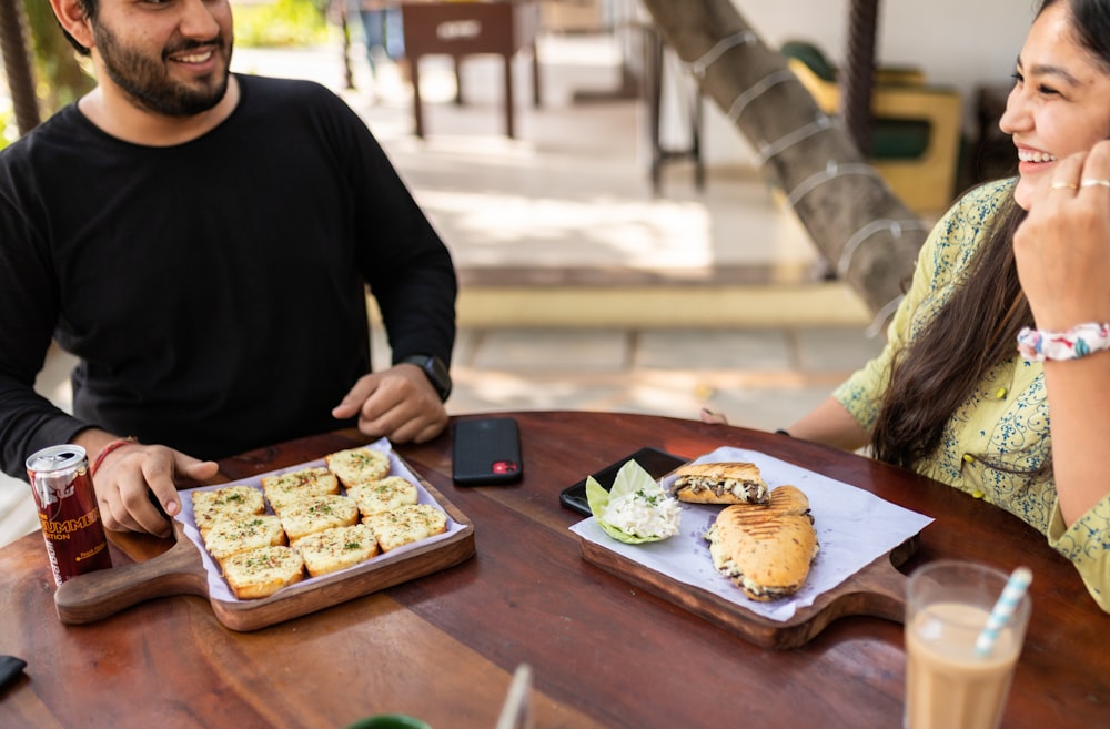 man in black long sleeve shirt holding brown pastry on brown wooden table