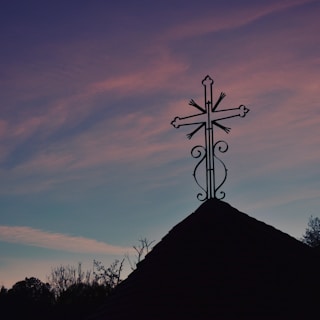 A peaceful church building with a cross silhouetted against a colorful sky