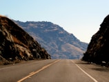 Aerial view of a newly paved highway cutting through mountainous terrain under clear skies.