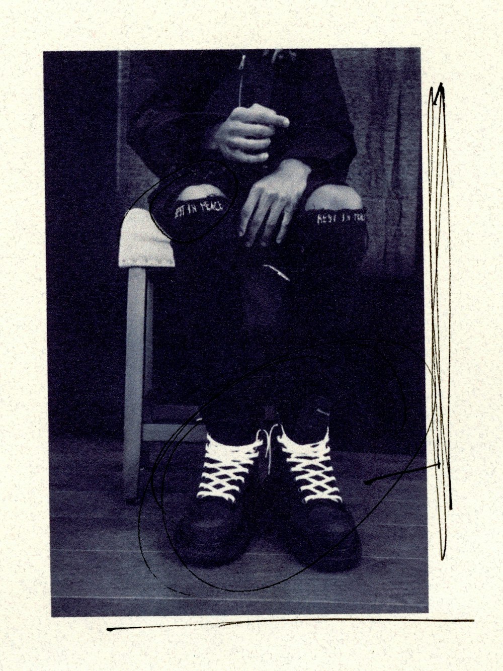 검은 재킷과 흑백 줄무늬 바지를 입은 남자가 흰색 의자에 앉아 있다
