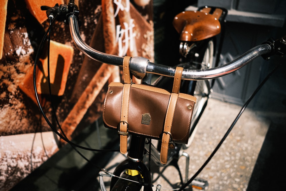 brown leather shoulder bag on black bicycle handle bar