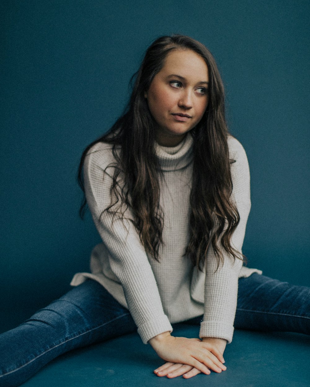 woman in white turtleneck sweater and blue denim jeans sitting on blue couch