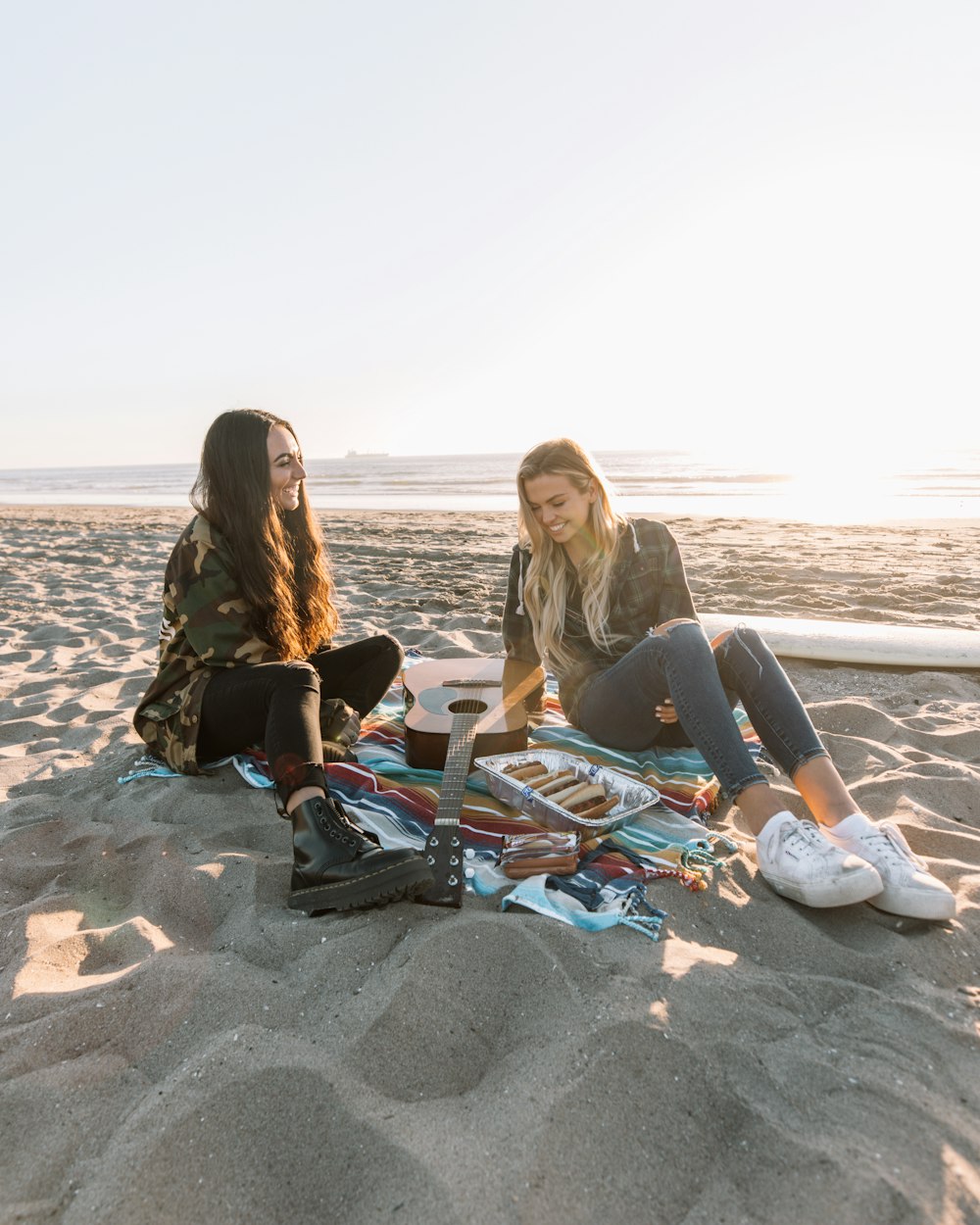 2 women sitting on beach shore during daytime