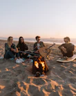 people sitting on sand near bonfire during daytime