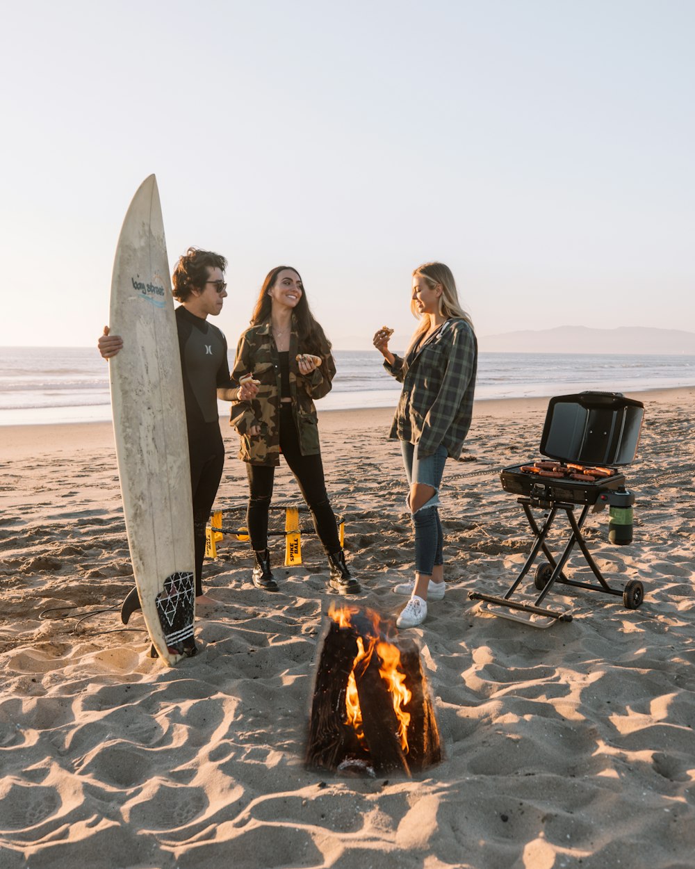 man and woman standing beside bonfire during daytime