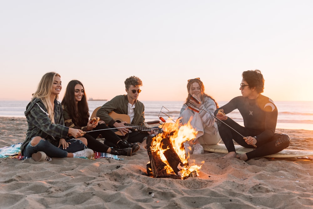 groupe de personnes assises sur le sol avec un feu de joie pendant la journée