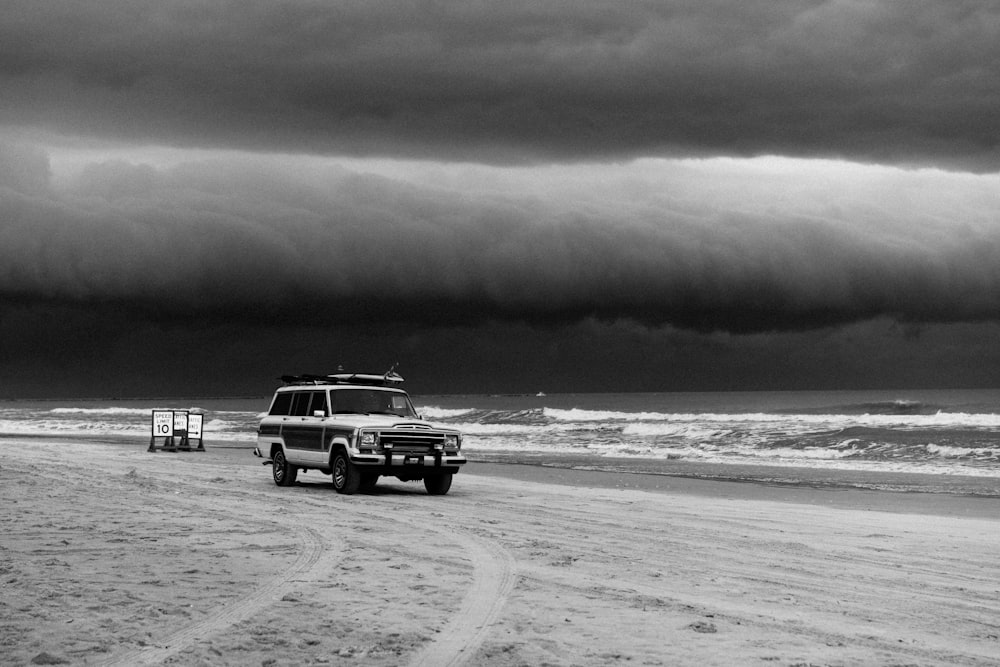 grayscale photo of car on beach