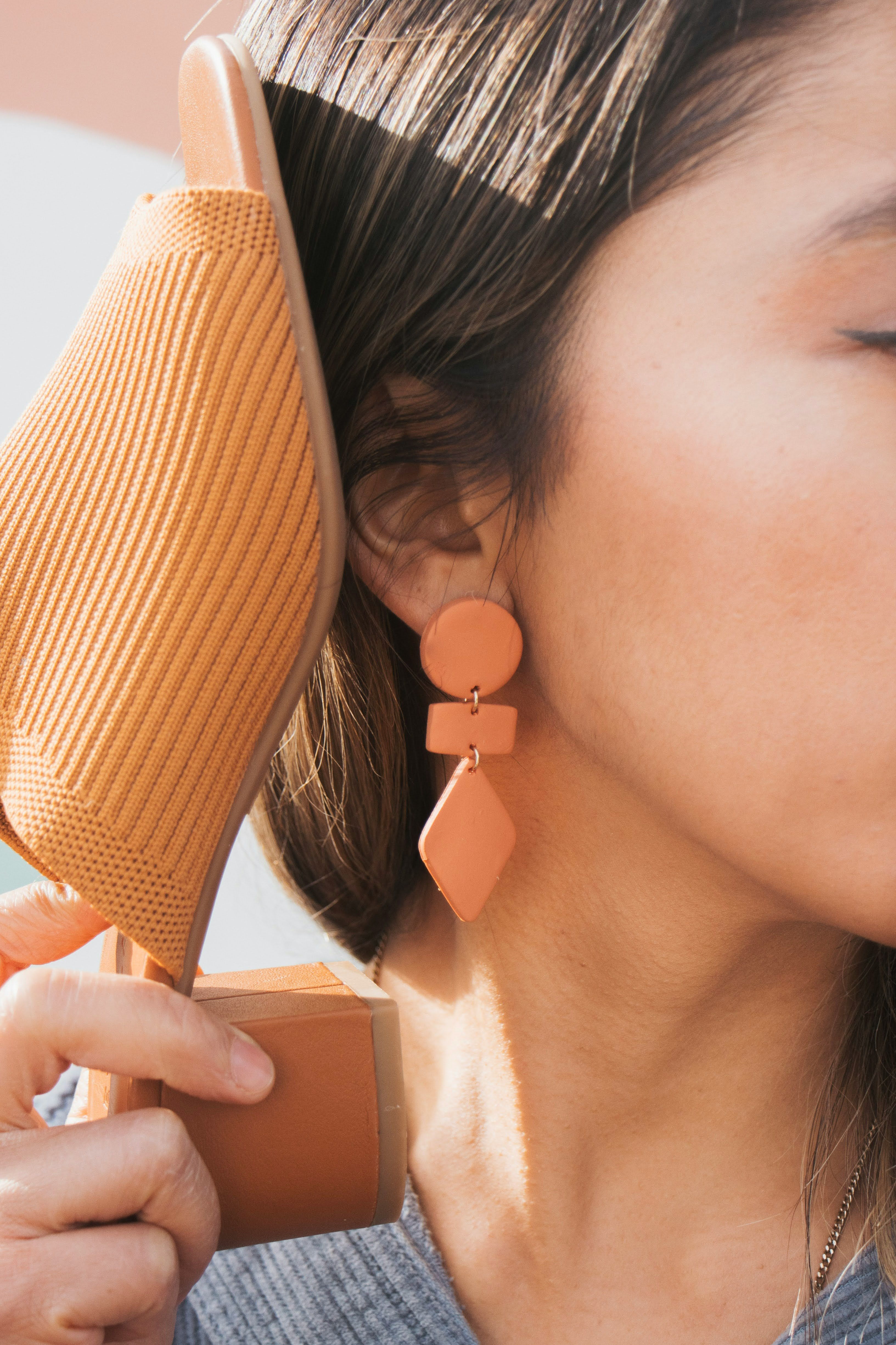 woman in white shirt wearing brown and white pearl stud earring