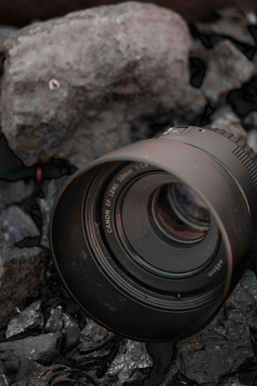black camera lens on gray rock