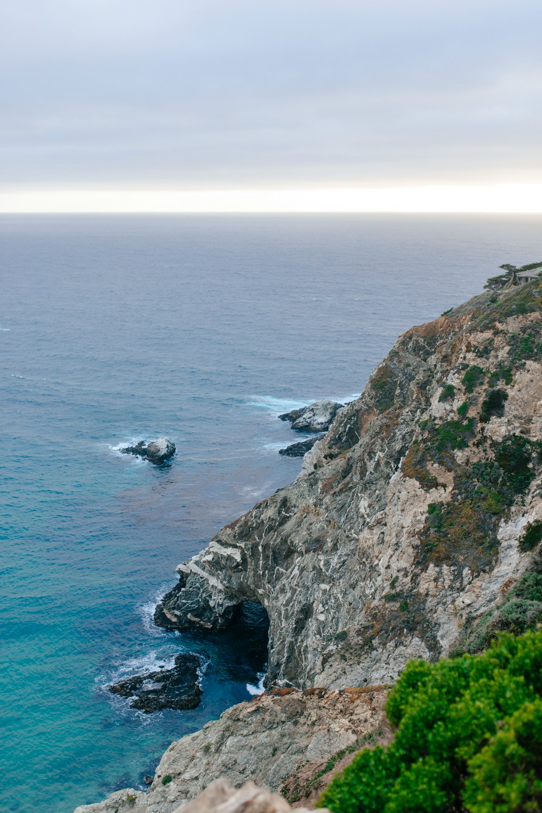 white boat on sea near brown and green cliff during daytime