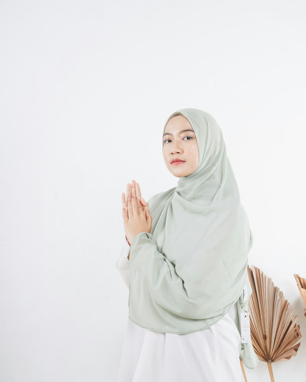 mulher no hijab branco que está perto da parede branca