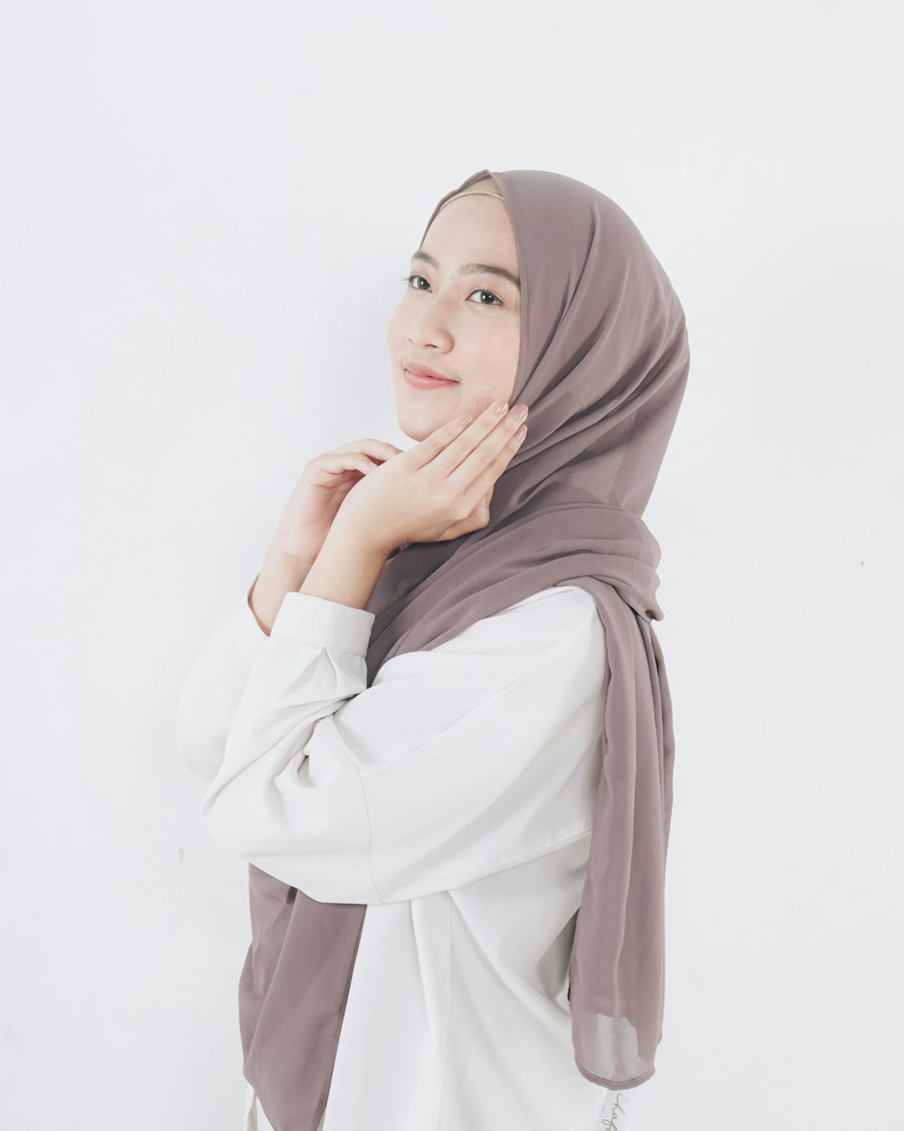 Mujer con camisa blanca de manga larga y hiyab marrón