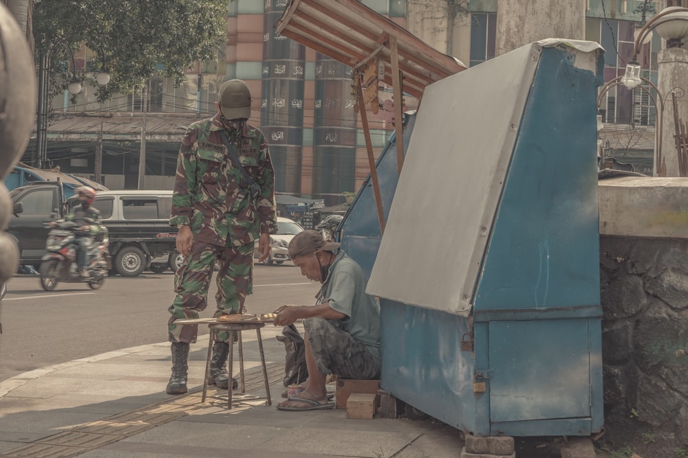 man in green and brown camouflage jacket standing beside blue bus during daytime