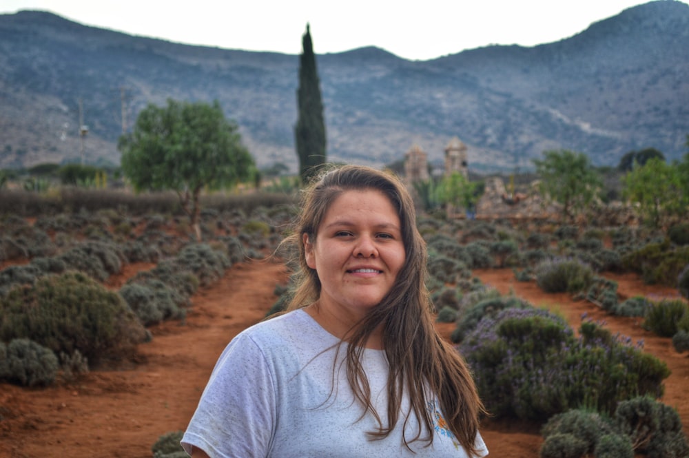 woman in white crew neck t-shirt standing on brown field during daytime