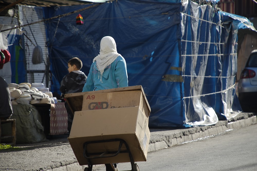 man in white thobe sitting on brown cardboard box