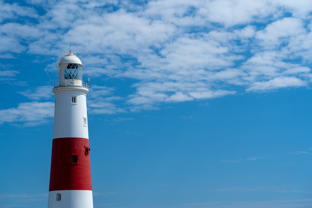 Faro rojo y blanco bajo el cielo azul durante el día