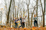 Children examining colorful leaves during a forest walk on a sunny day.
