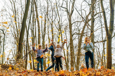 Children playing happily near a wooden cabin with a backdrop of soft autumn leaves.