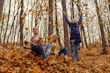 Little girl bundled in a cozy jacket playing in autumn leaves