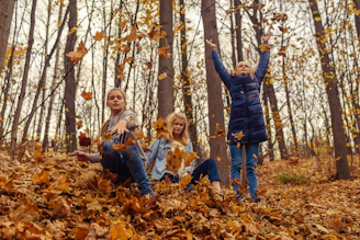 Children enjoying a vibrant autumn day outside, surrounded by colorful falling leaves.