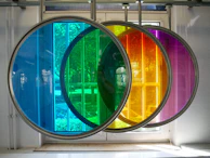 A vibrant, backlit glass panel installed in a modern interior, casting colorful reflections.