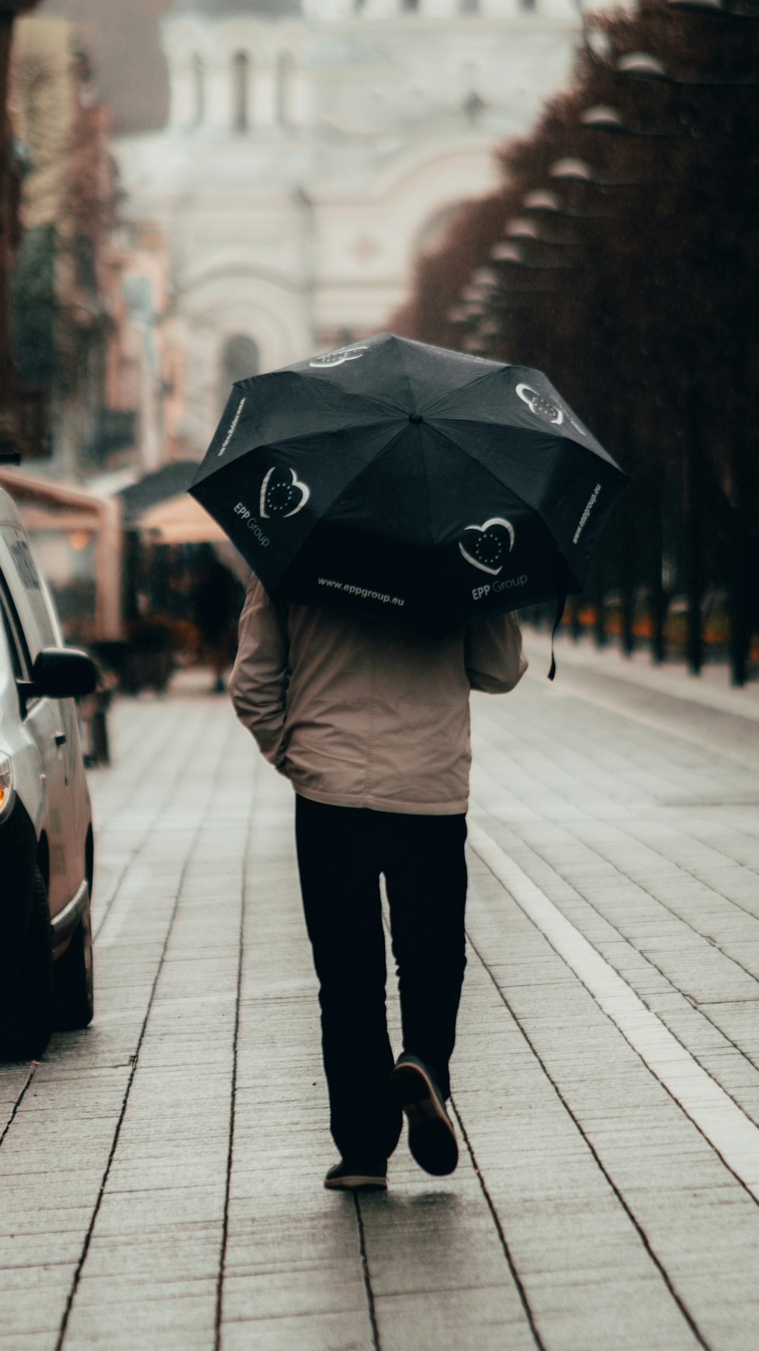 woman in beige sweater and black pants holding umbrella