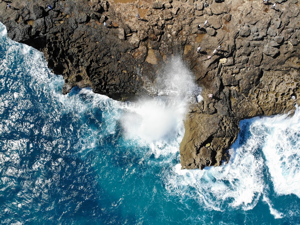 sea waves crashing on brown rock formation during daytime