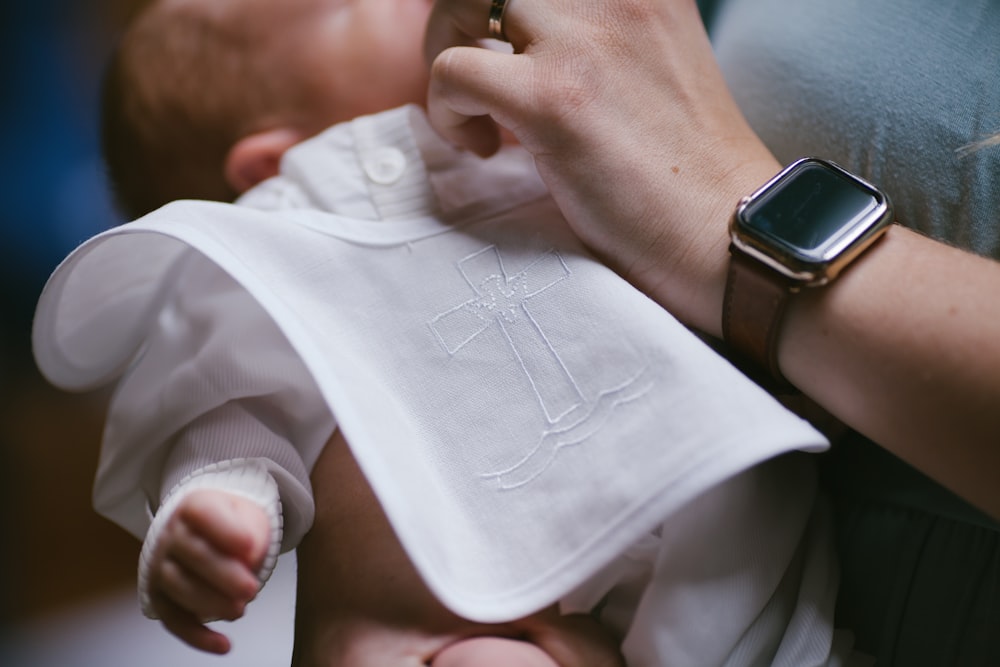 person holding babys white onesie