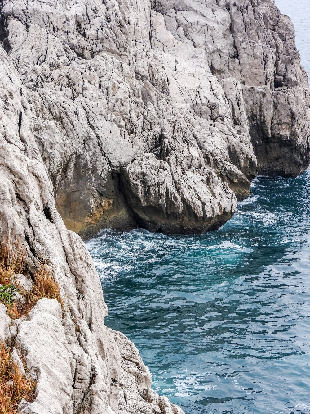 brown rocky mountain beside blue sea during daytime