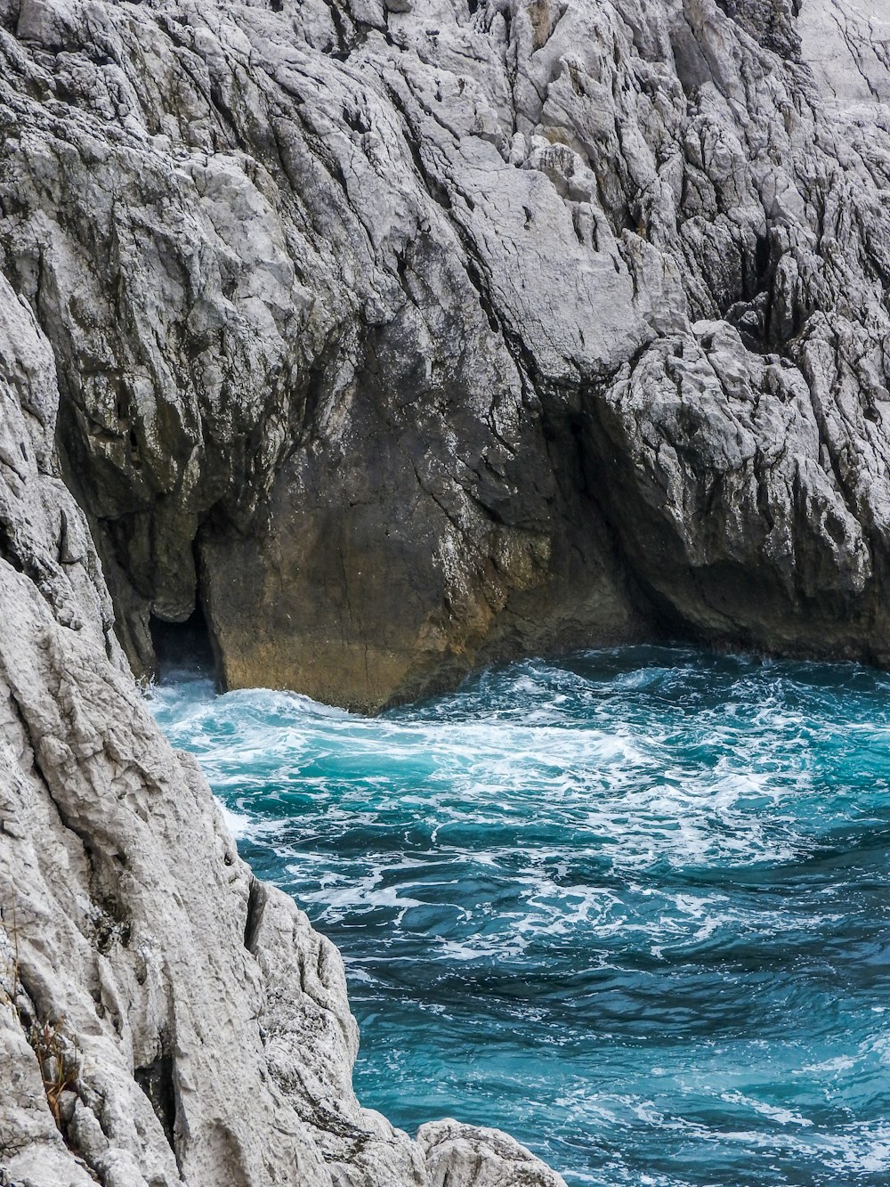 gray rock formation beside body of water during daytime