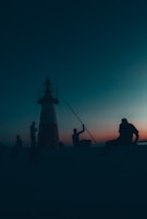 silhouette of 2 people sitting on the edge of a building
