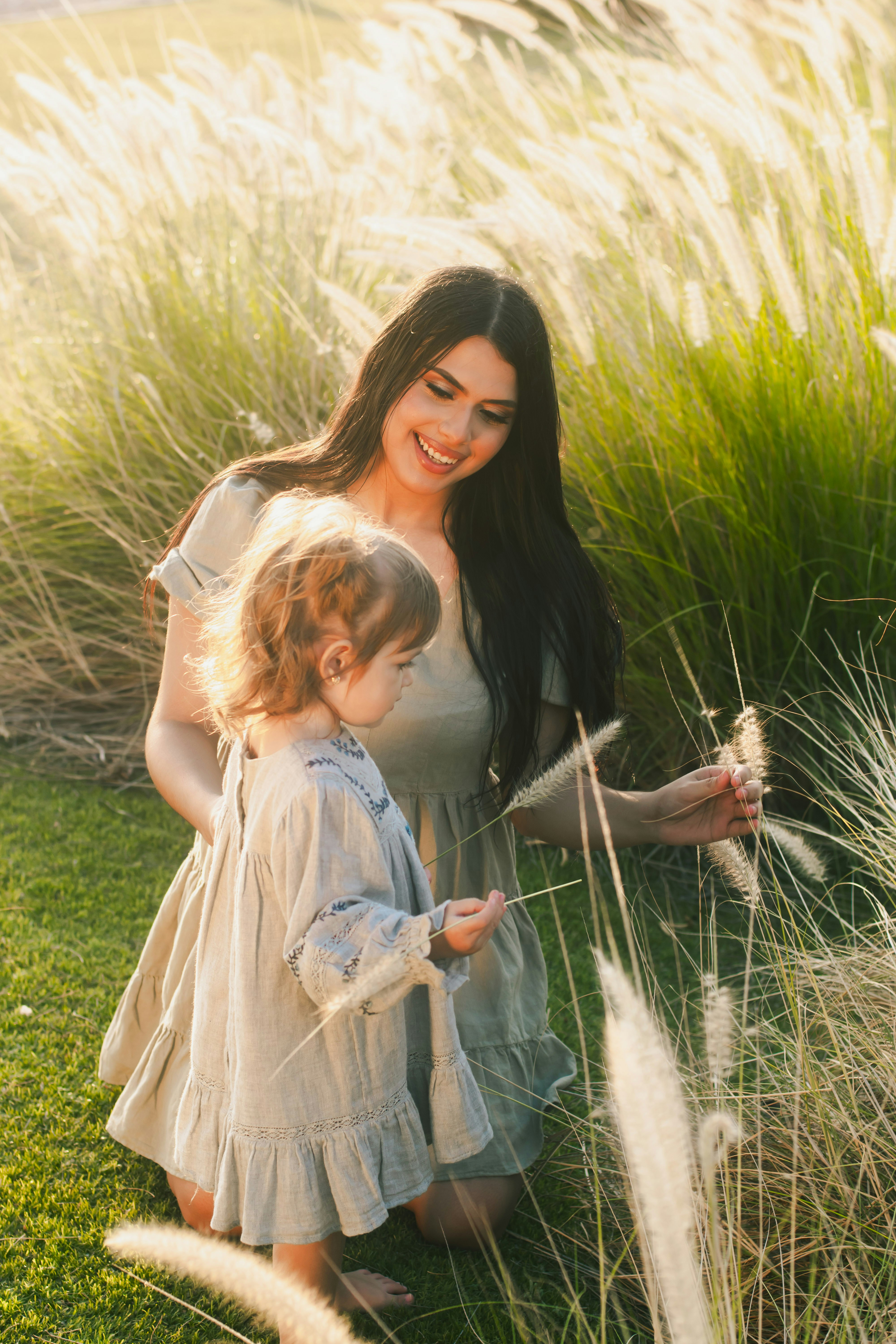 woman in black cardigan carrying girl in blue dress