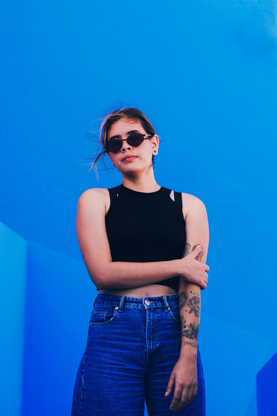 woman in black tank top and blue denim jeans wearing black sunglasses