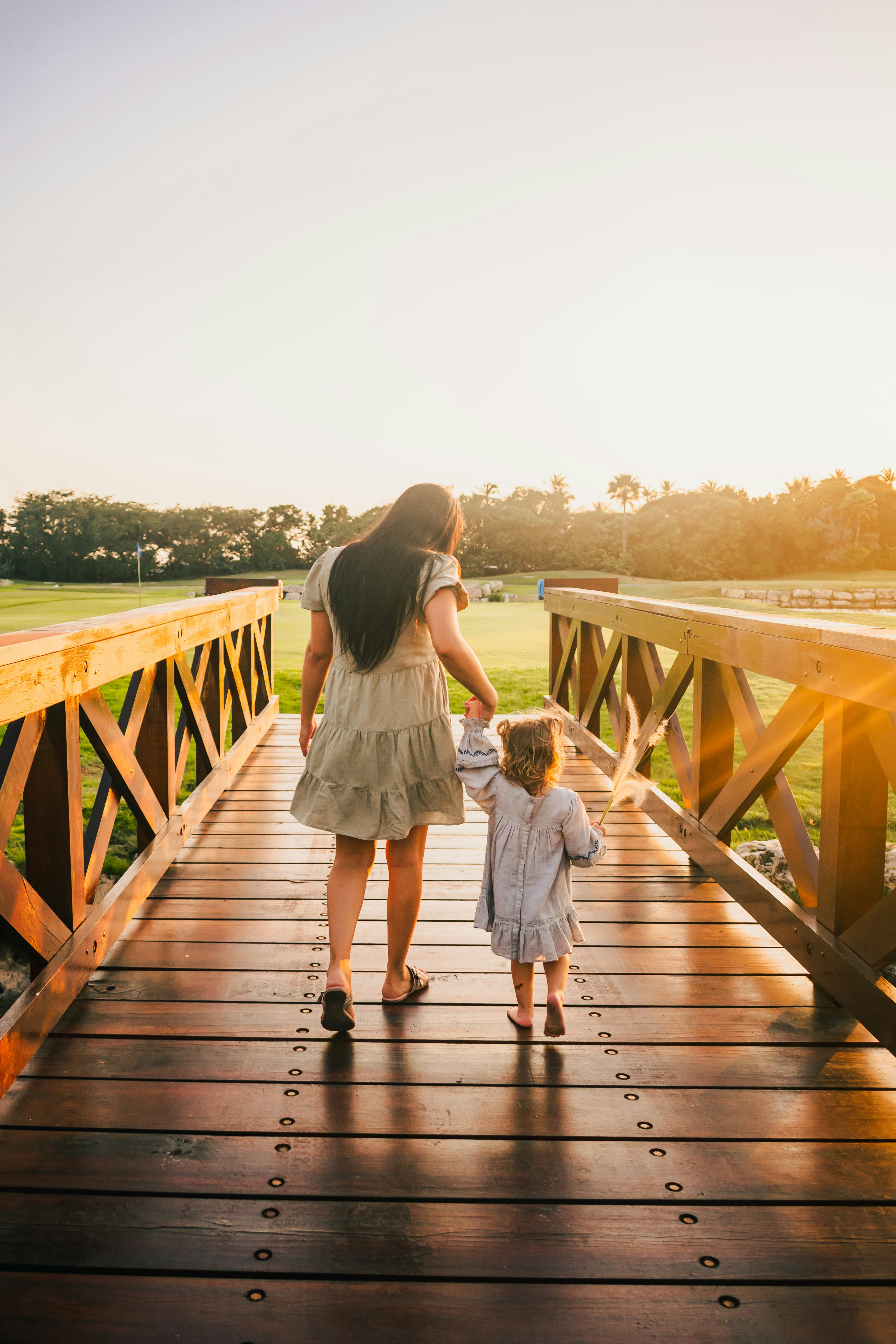 woman in white dress walking on wooden bridge during daytime