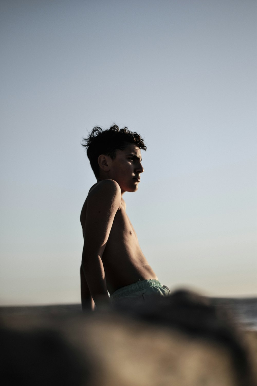 topless woman in blue denim shorts standing on beach during daytime