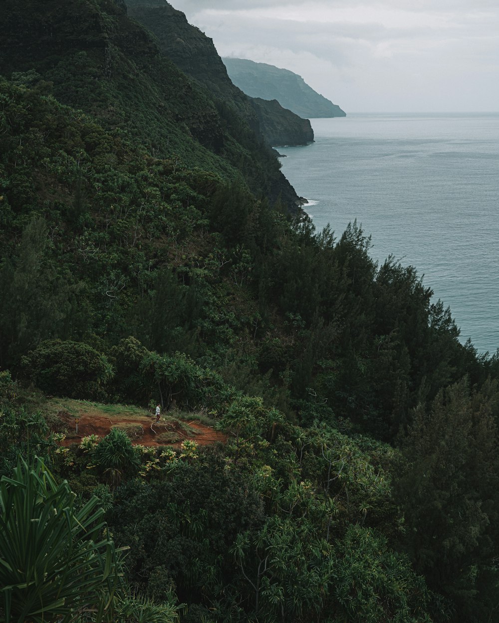 green and brown mountain beside body of water during daytime