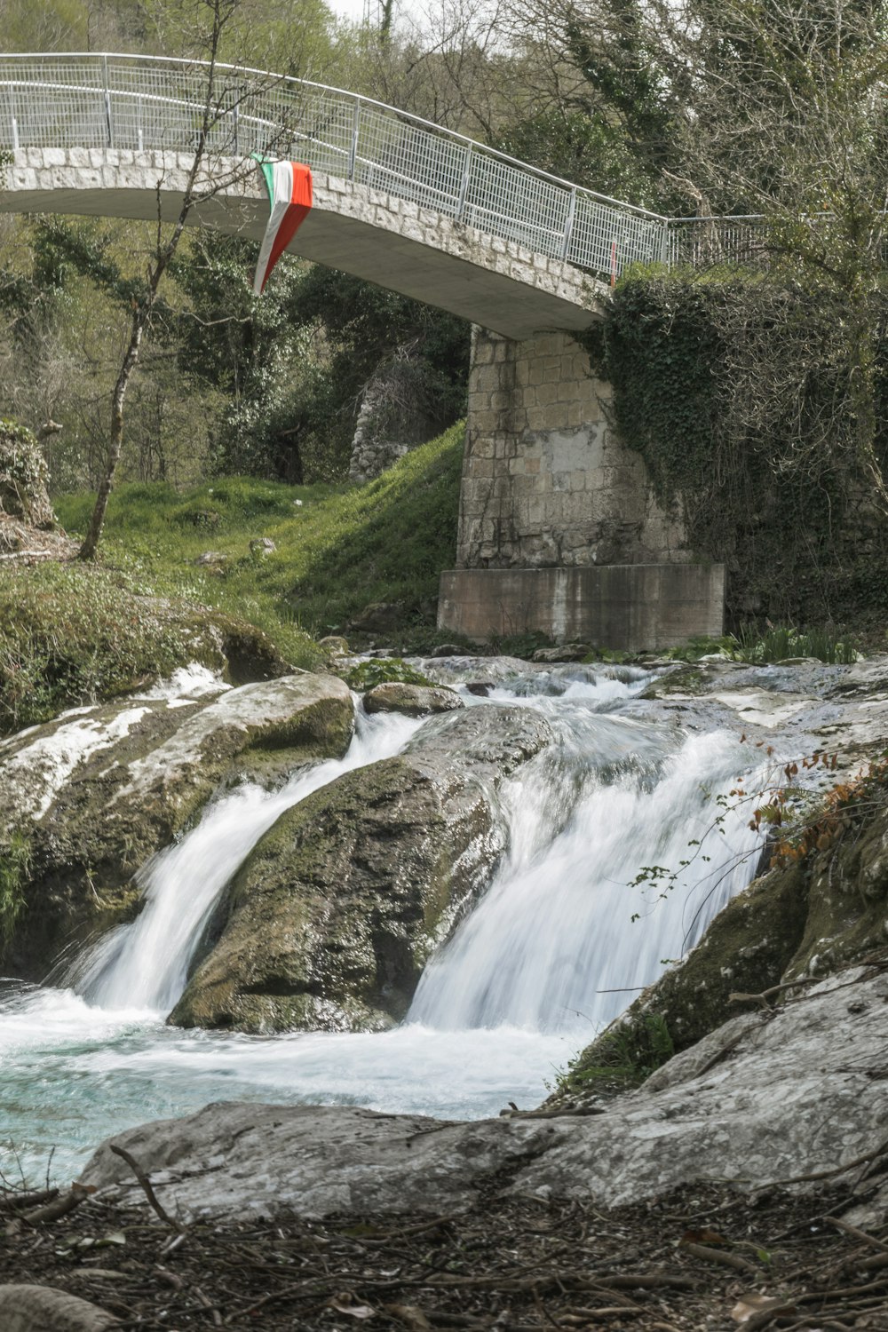 waterfalls under bridge during daytime