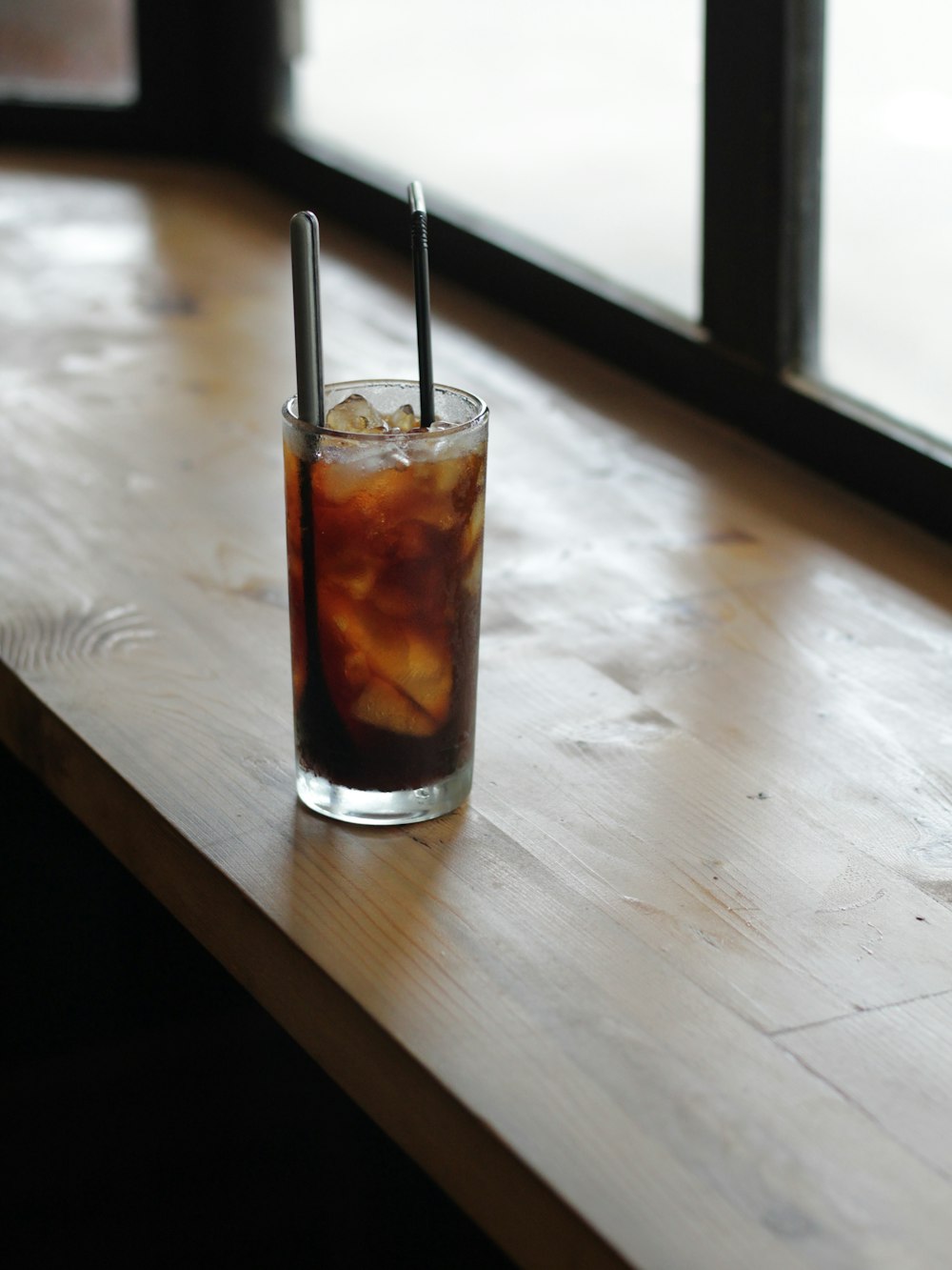 clear drinking glass with black straw on white table