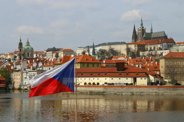 Red and white concrete building near body of water during daytime — Prague, Czech Republic