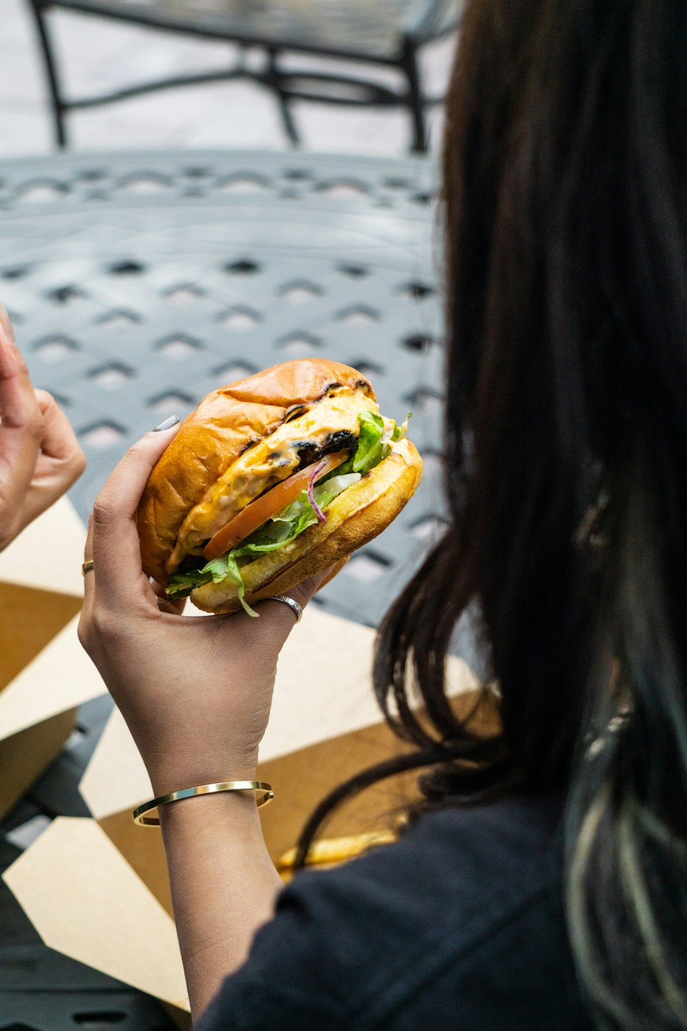 person holding burger with patty and lettuce