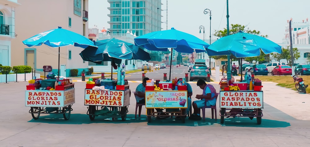 personas sentadas en sillas rojas bajo sombrilla azul durante el día