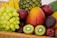 red apple fruit beside green apple and yellow fruit on brown woven basket