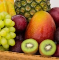 red apple fruit beside green apple and yellow fruit on brown woven basket