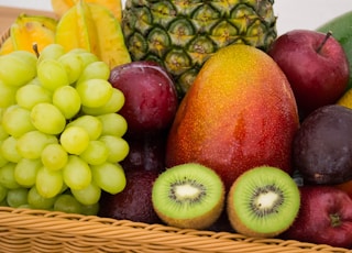 red apple fruit beside green apple and yellow fruit on brown woven basket