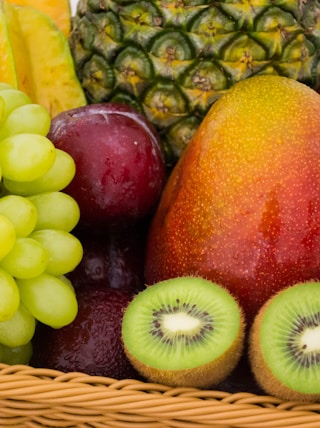 red apple fruit beside green apple and yellow fruit on brown woven basket