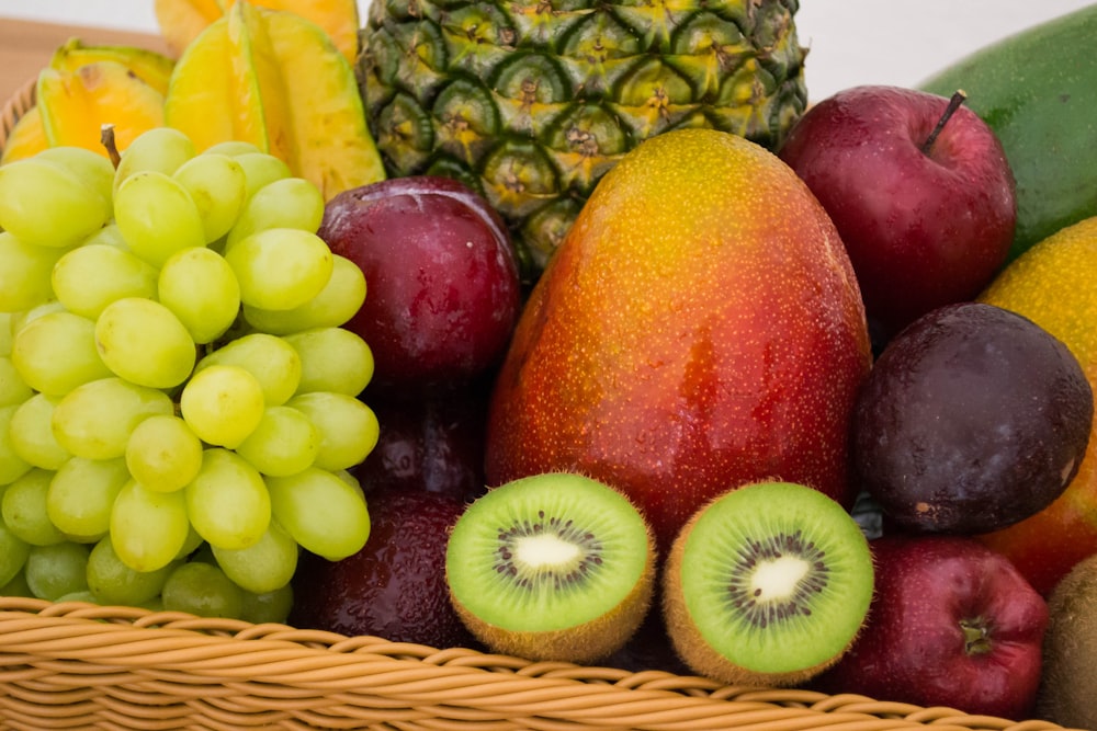 red apple fruit beside green apple and yellow fruit on brown woven basket